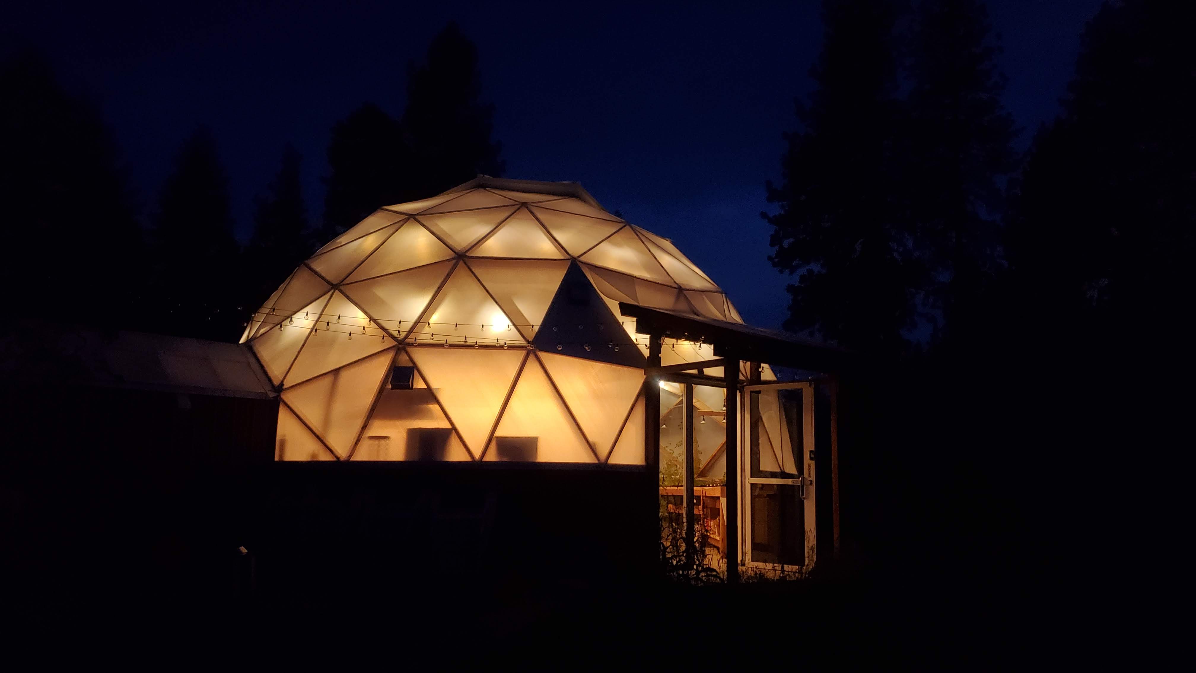 The greenhouse dome glowing warmly on a summer night