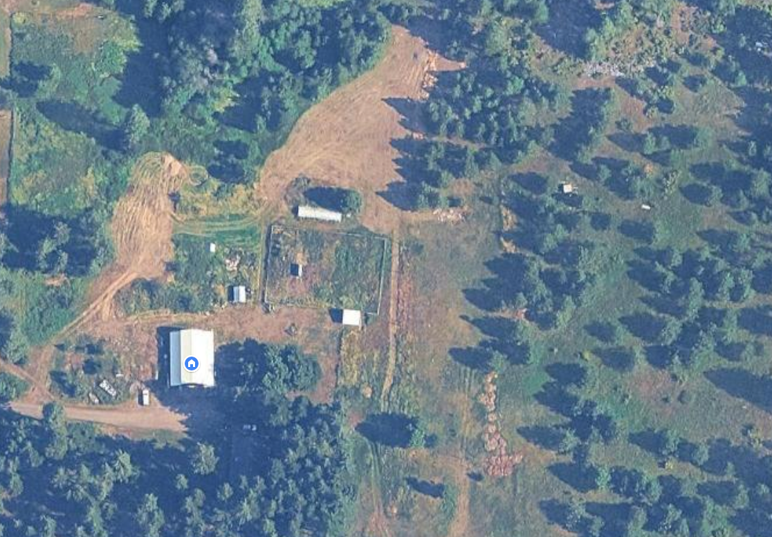 Aerial view of Brand Family Farm LLC surrounded by evergreen forest